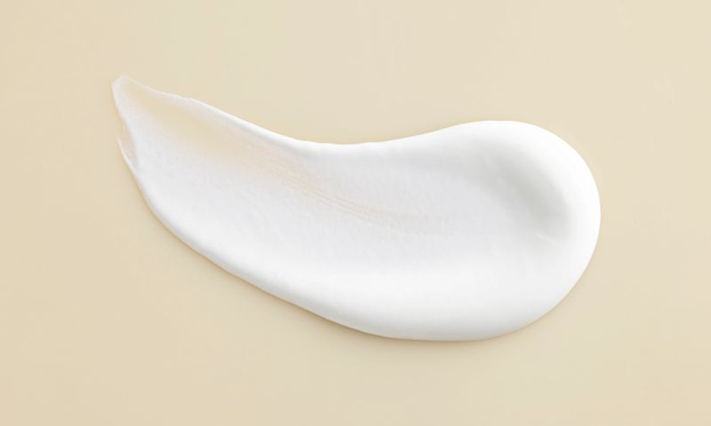 A delicate white cream positioned on a white surface showcasing its soft texture and uniform color