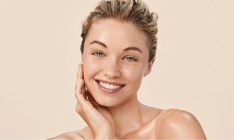 Happy woman with Aveeno Calm + Restore skincare for sensitive skin.