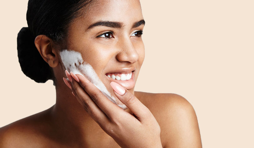 Person gently applying a foaming facial cleanser to their skin as part of a skincare routine