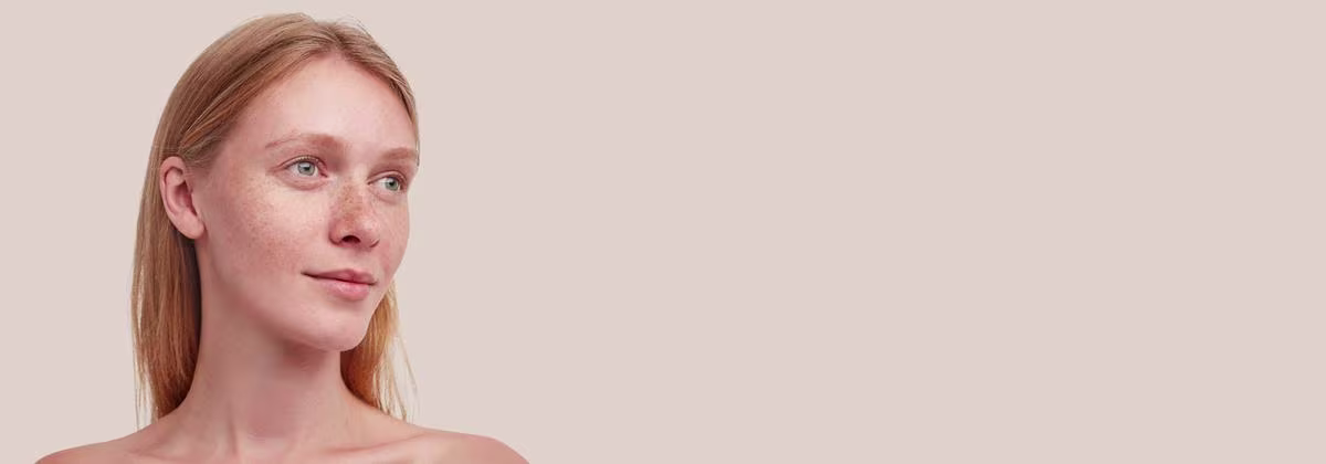 Dull skin banner with a woman smiling softly with her hair loosely styled and a natural background