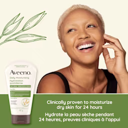 Woman smiling with Aveeno Daily Moisturizing Face Cream tube and text stating 'Clinically proven to moisturize dry skin for 24hrs'.