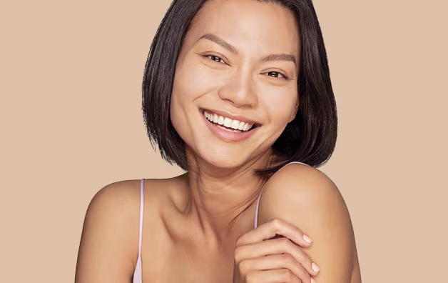 Woman with short dark hair holding her left arm and smiling