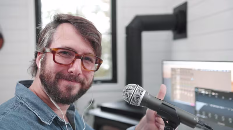 a man wearing headphones and sitting in front of a microphone