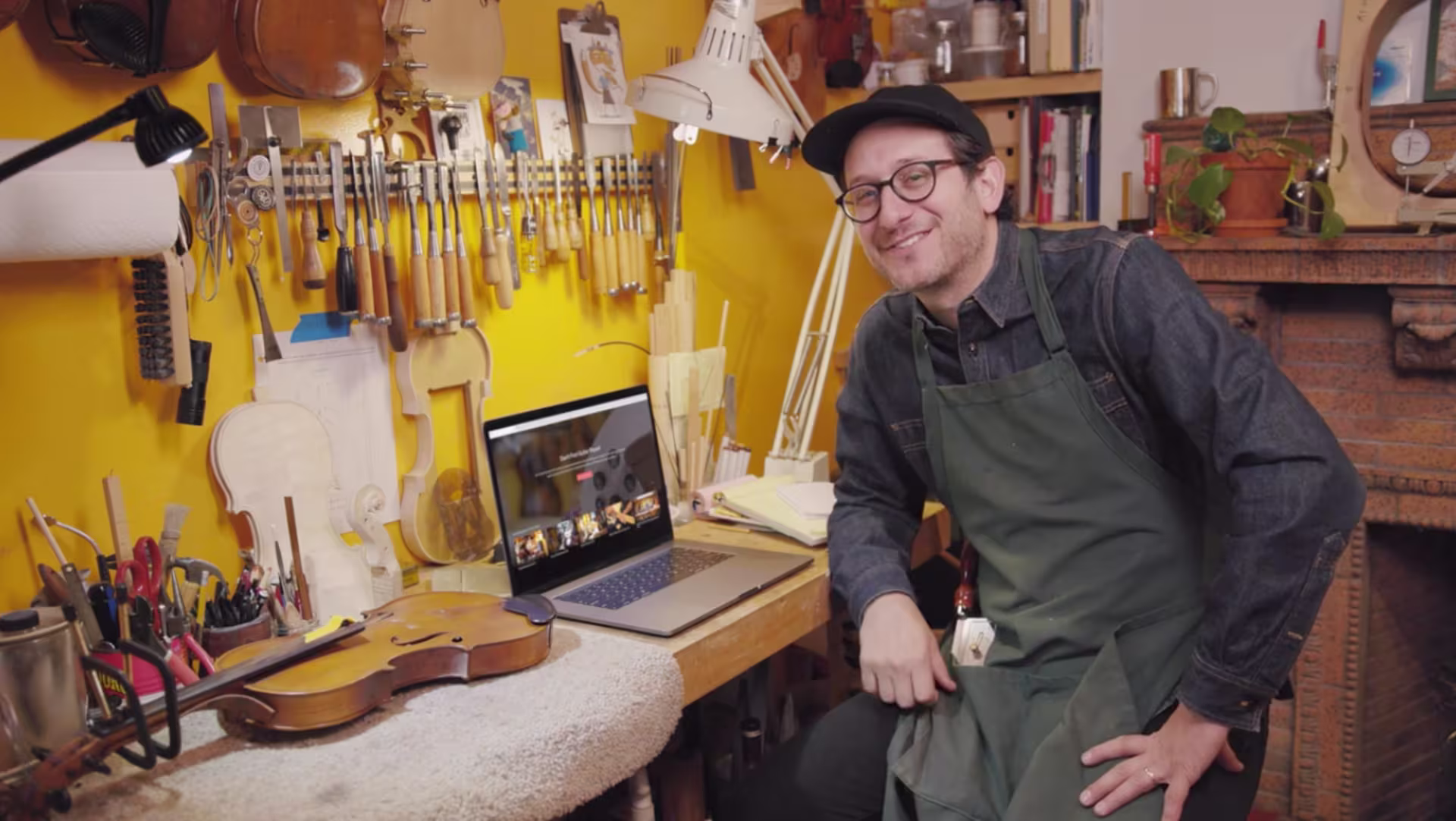 a man sitting in a guitar shop with a computer in front of him