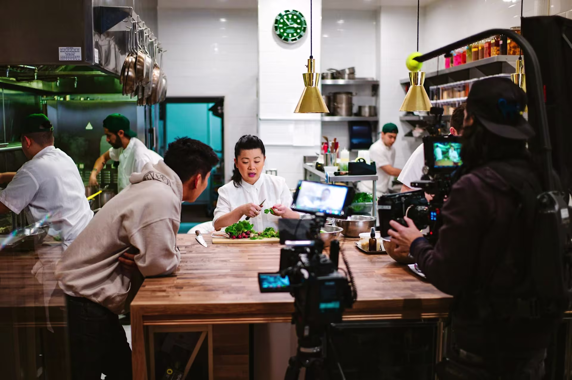 woman being filmed cooking in a restaurant at a wooden table