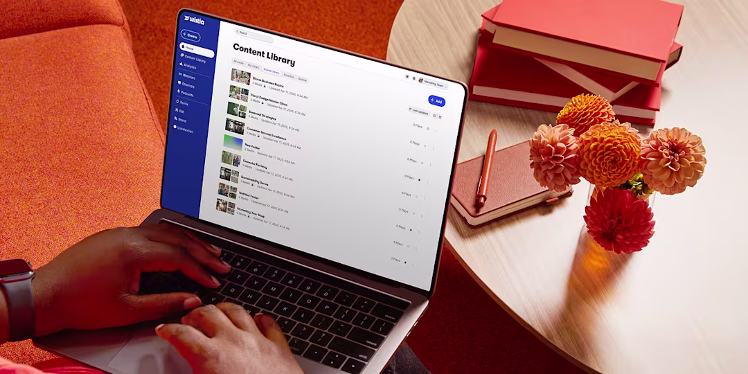 The hands of someone typing away on a laptop. Screen shows the Wistia media library.