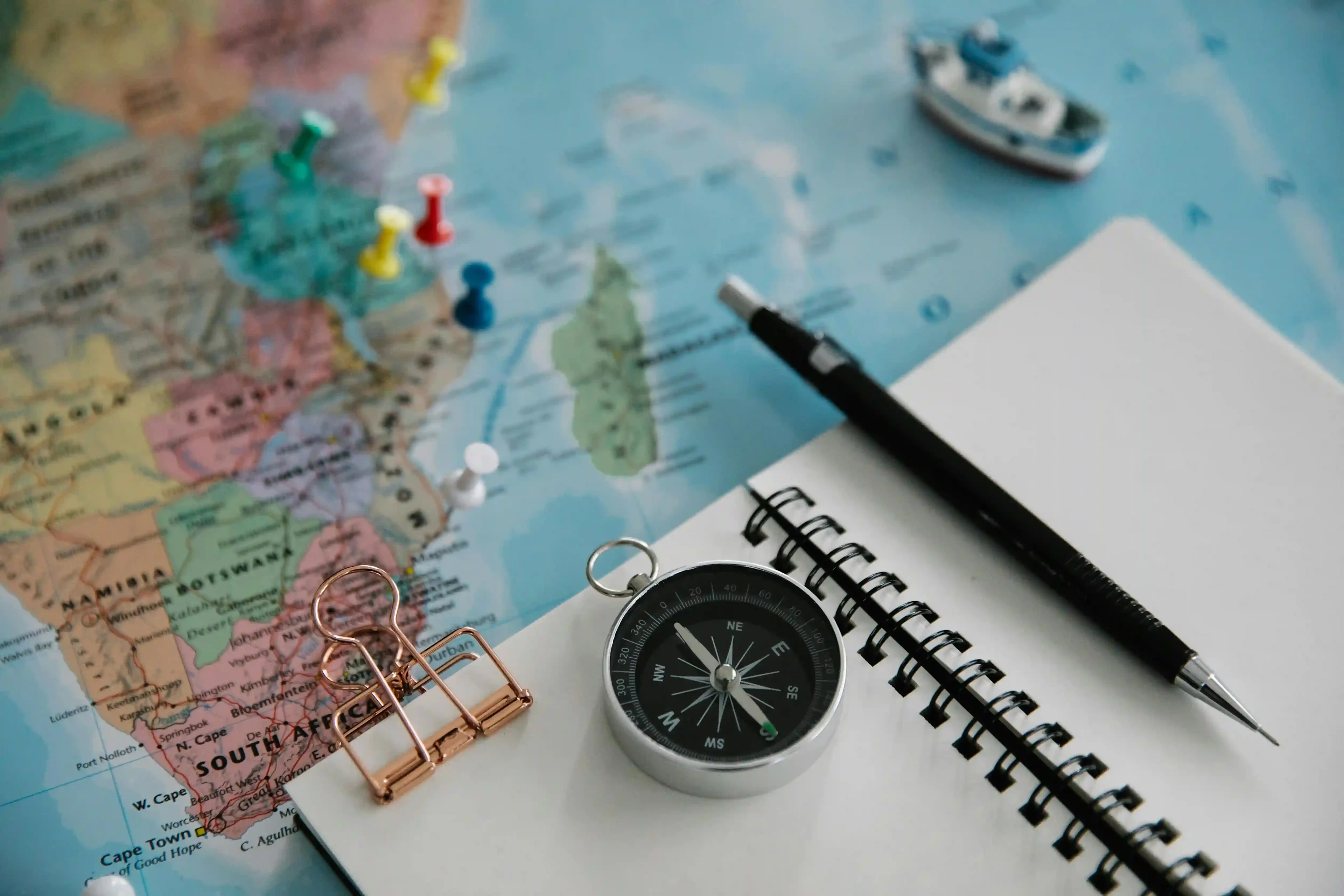 compass, notebook and pen on a world map