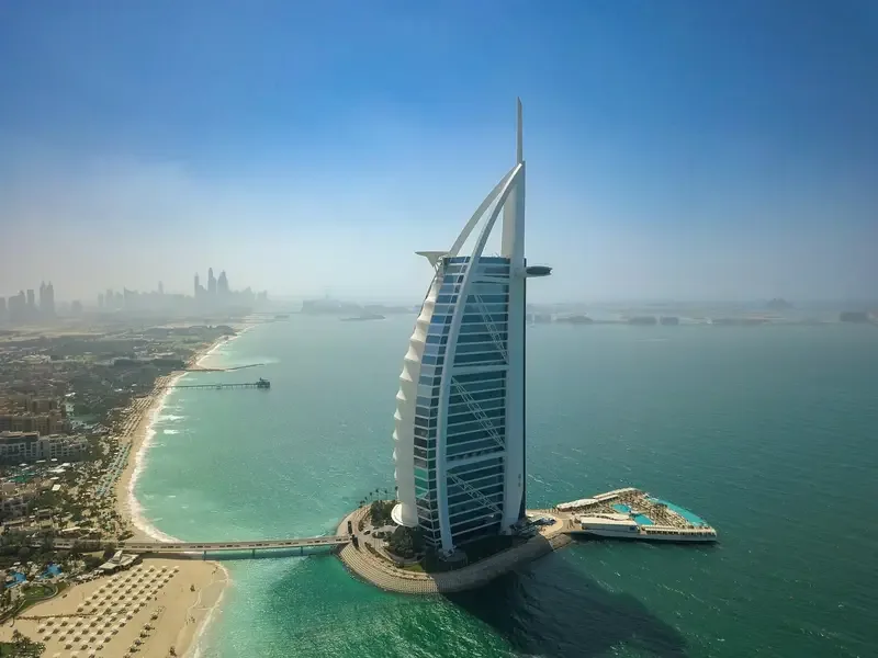 Aerial view of the Burj Al Arab hotel in Dubai, surrounded by turquoise sea and coastline