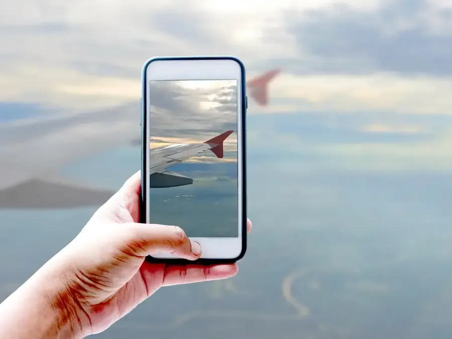 hand holding a phone taking a photo of a plane