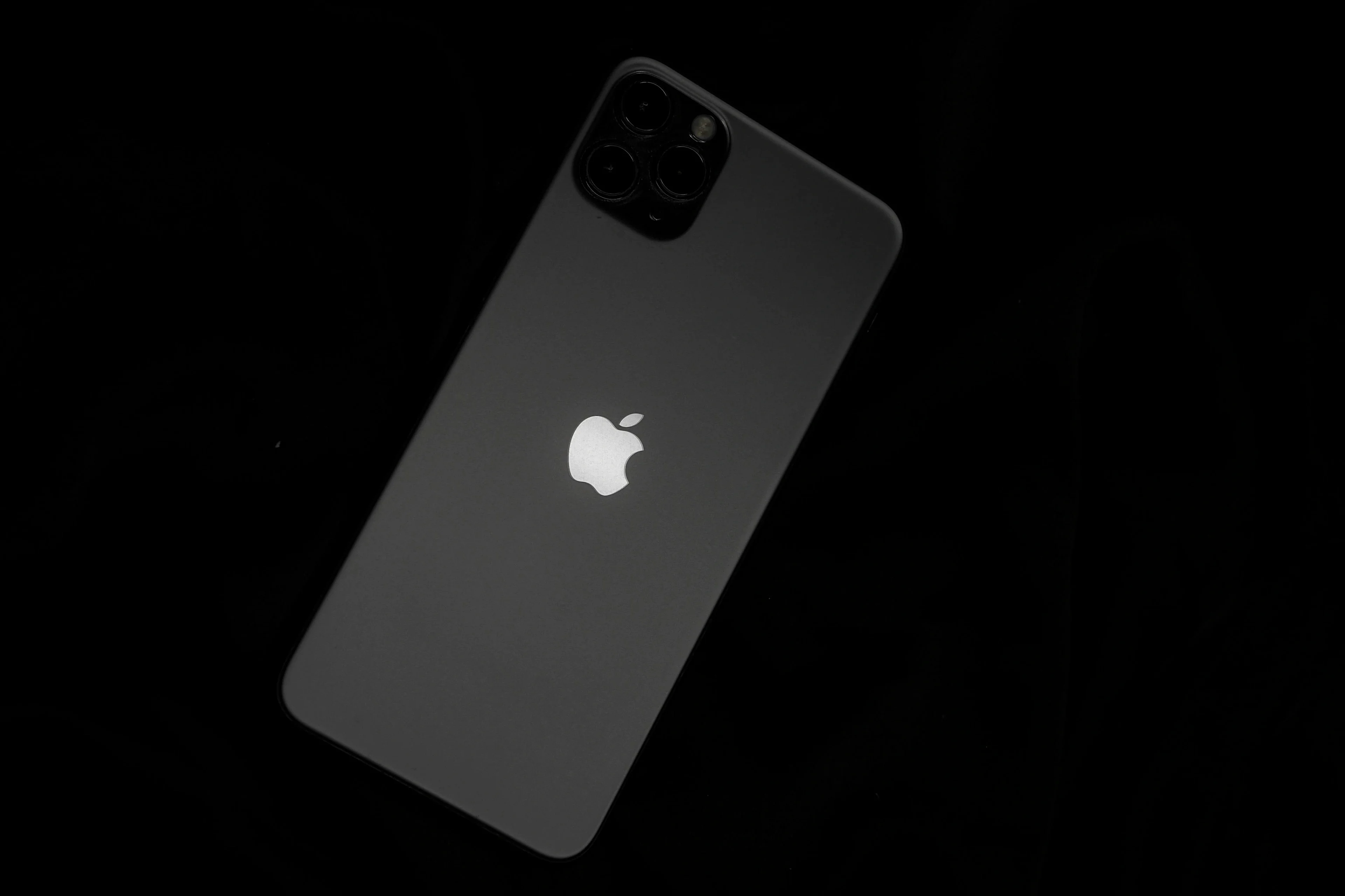 Back of a black iPhone with Apple logo on dark background