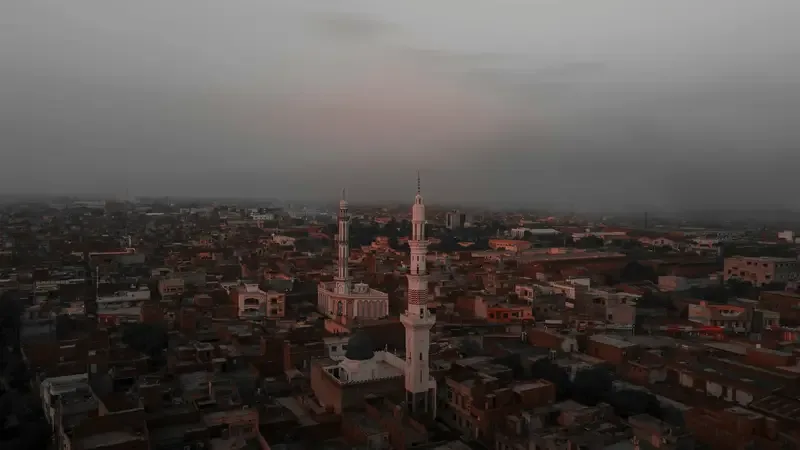Aerial view of a Pakistani city with two tall mosque minarets at dusk
