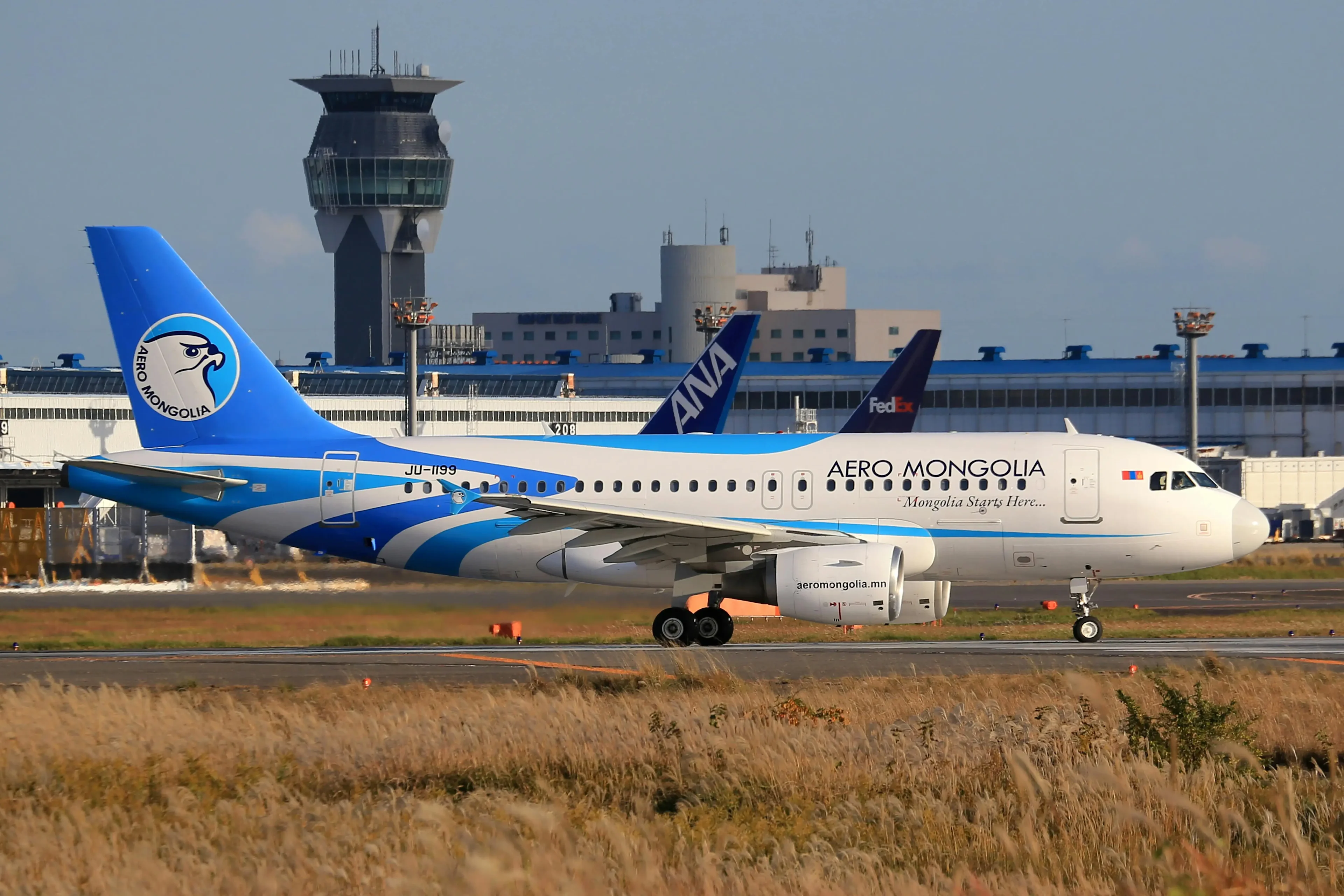 A white airplane with blue wings taking off at the airport