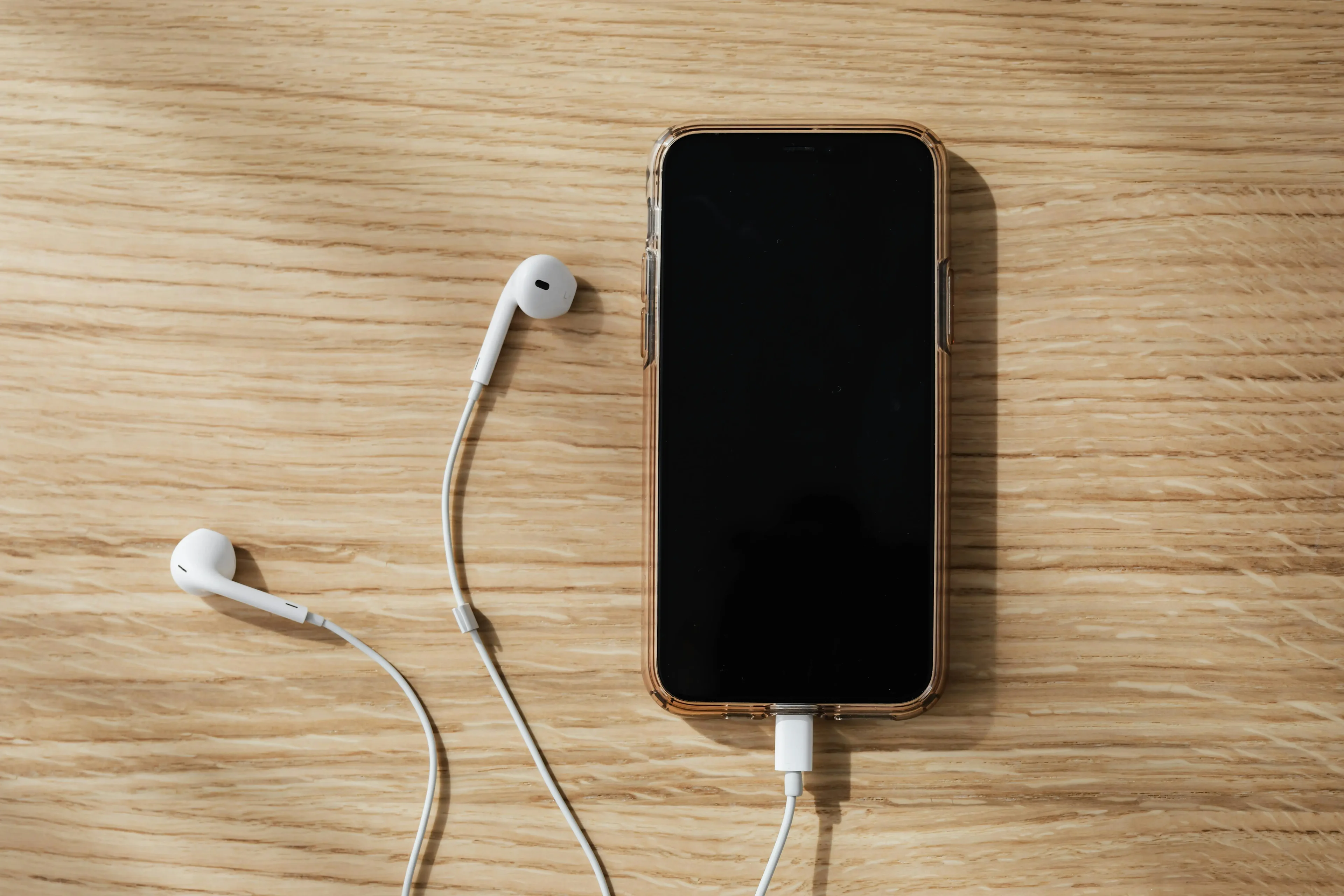 Smartphone with wired earphones placed on a wooden surface