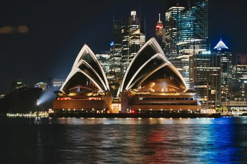 Sydney Opera House at night with city lights and water reflections