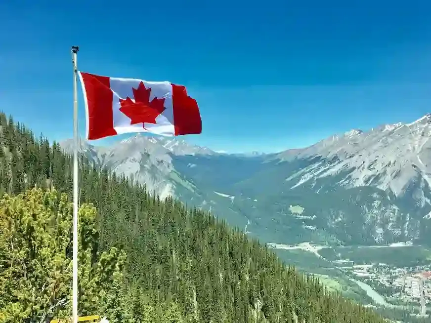 canada flag in front of a mountainous scenery