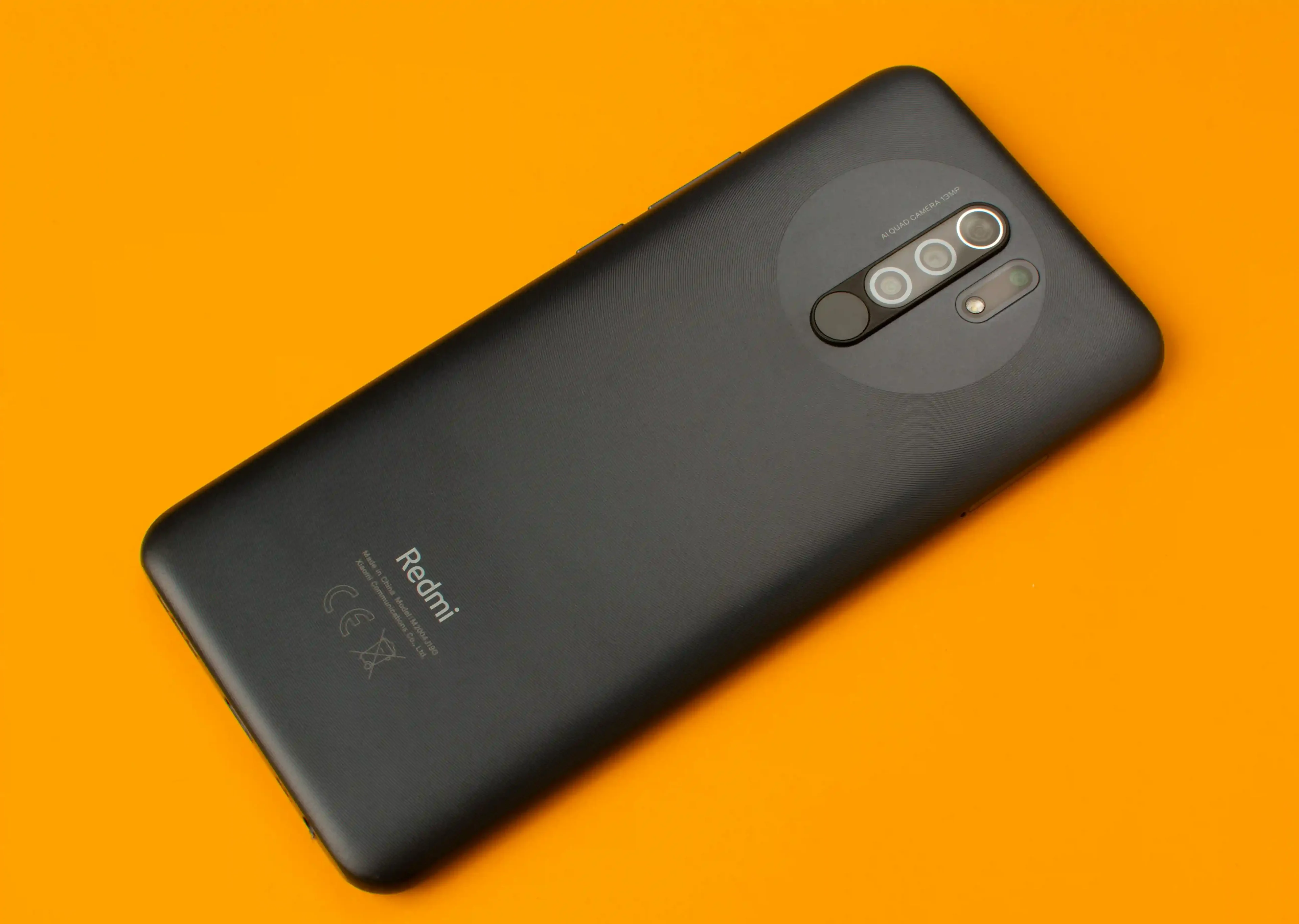 A black Xiaomi phone on an orange background