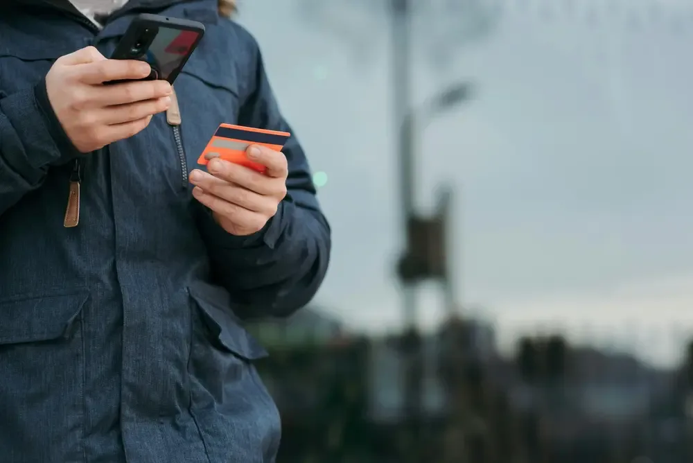 a person holding smartphone and credit card