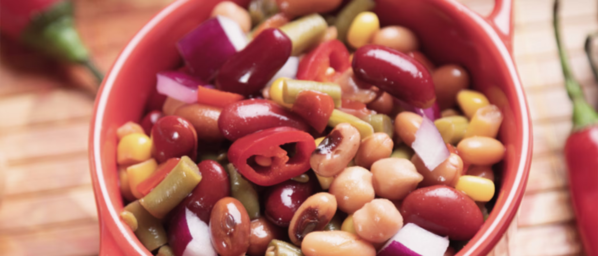 A bowl of colorful bean salad with kidney beans, corn, peppers, and onions.
