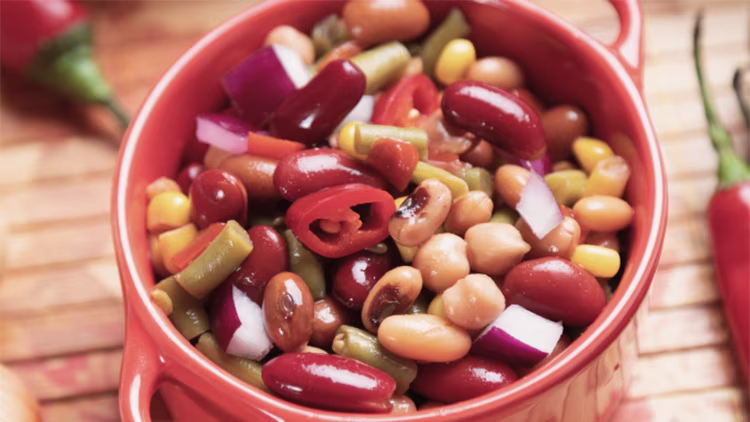 A bowl of colorful bean salad with kidney beans, corn, peppers, and onions.