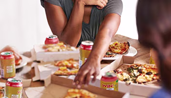 2 friends having pizza and sodas, indicating overindulgence.