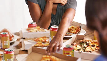 2 friends having pizza and sodas, indicating overindulgence.