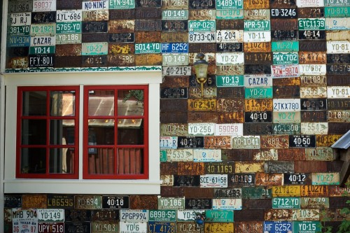 Photo d'un mur couvert de plaques d'immatriculation anciennes.