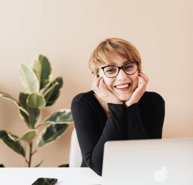 Een glimlachende vrouw werkt achter haar computer.