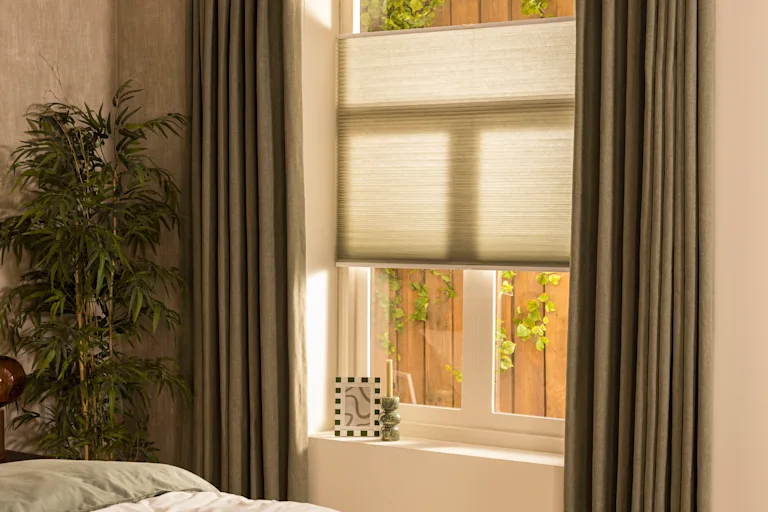 Groene gordijnen en groene plisségordijnen voor een raam in de slaapkamer