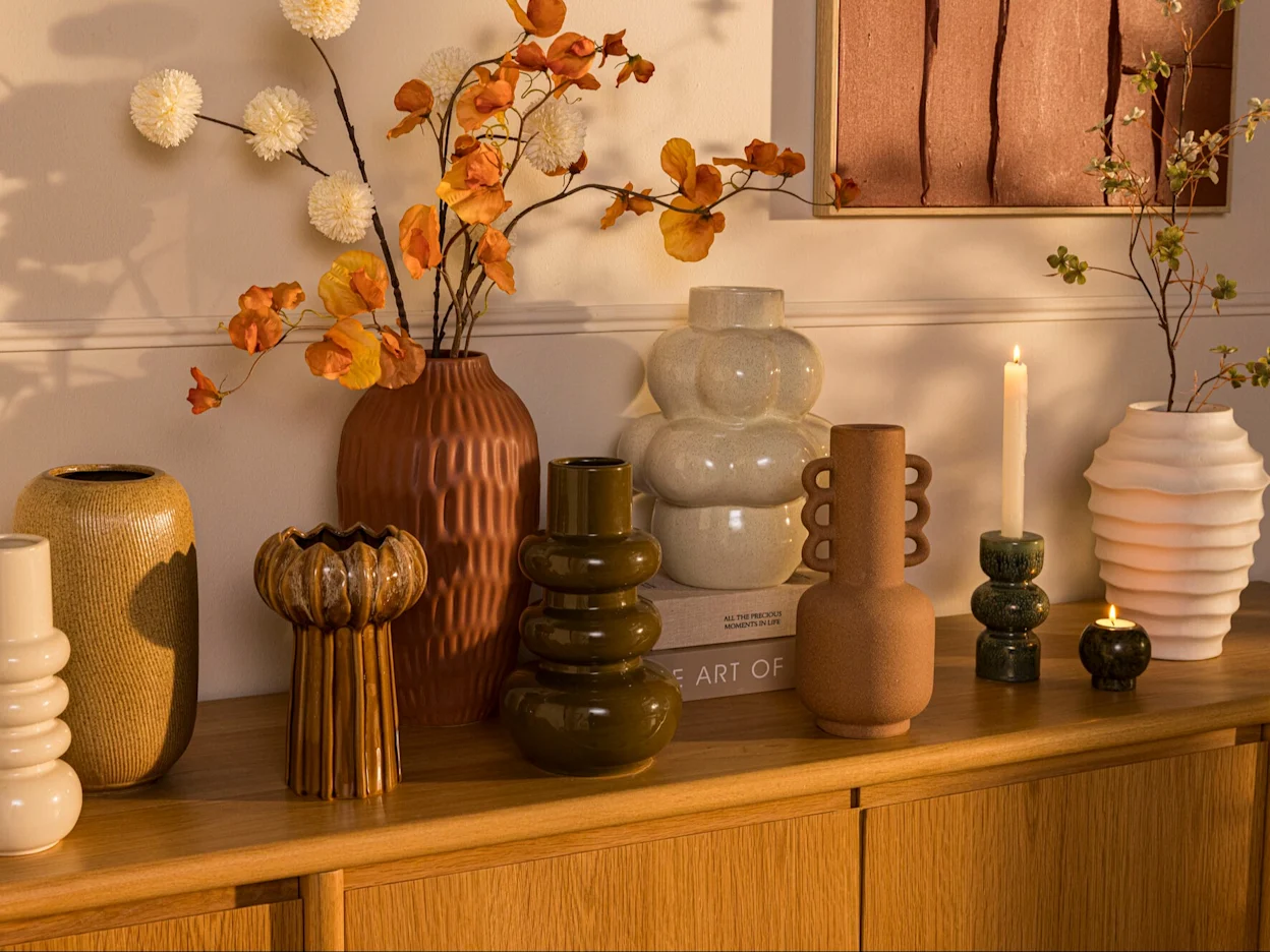 Houten dressoir met decoratie en vazen in een warm interieur.