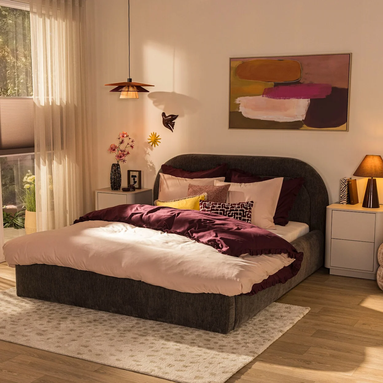 Warme slaapkamer met donker bed, licht beddengoed, sierkussens en lichte nachtkastjes.
