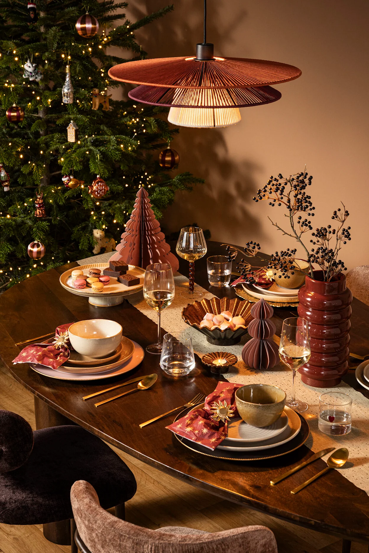 Feestelijk gedekte kersttafel met bordeaux, rood en gouden kerstdecoratie.