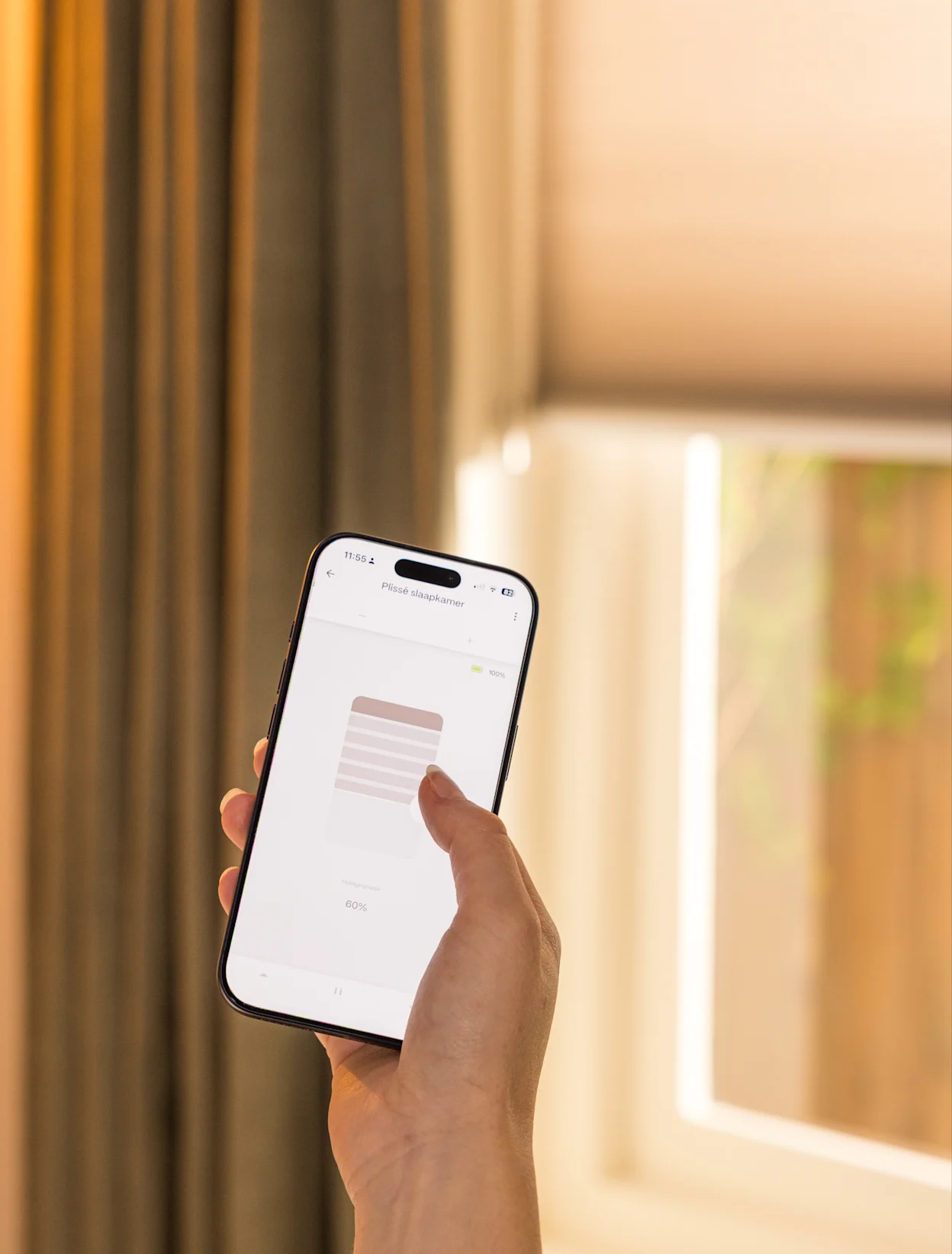 Hand met smartphone bij een raam met gordijnen.