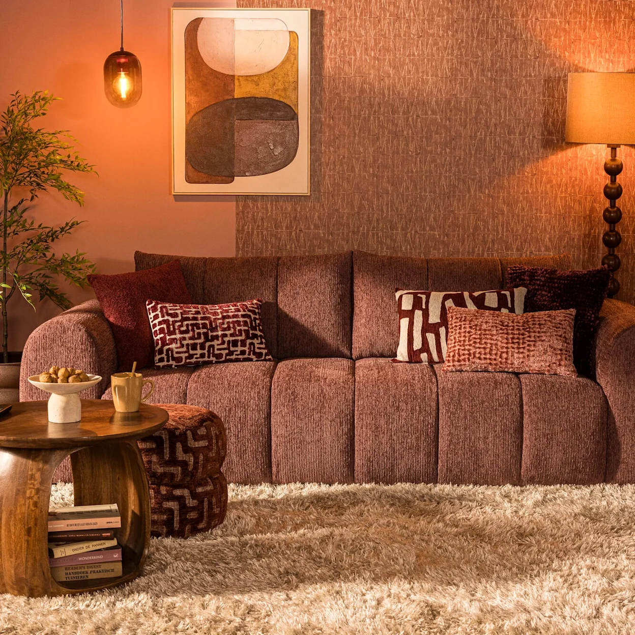 Warme woonkamer met mauve kleurige bank, sierkussens en houten salontafel.