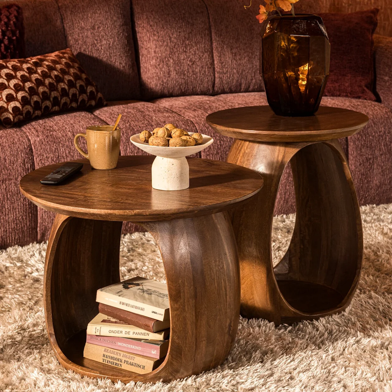Ronde houten salontafels met warme woonaccessoires en mauve kleurige bank