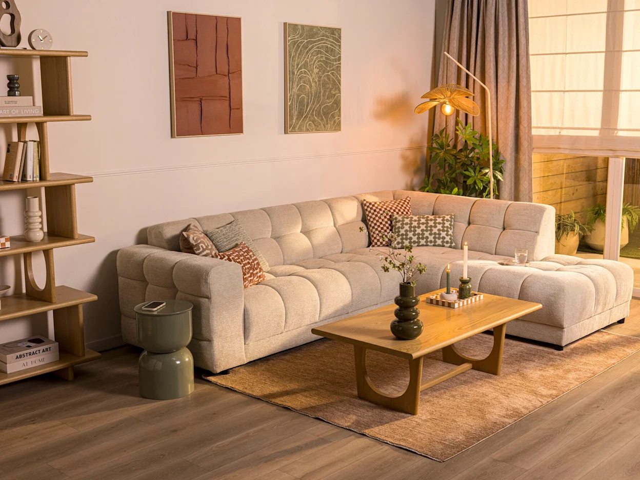 Natuurlijke woonkamer met lichte hoekbank, houten salontafel, schilderijen aan de wand en een lichtbruin vloerkleed op de grond.