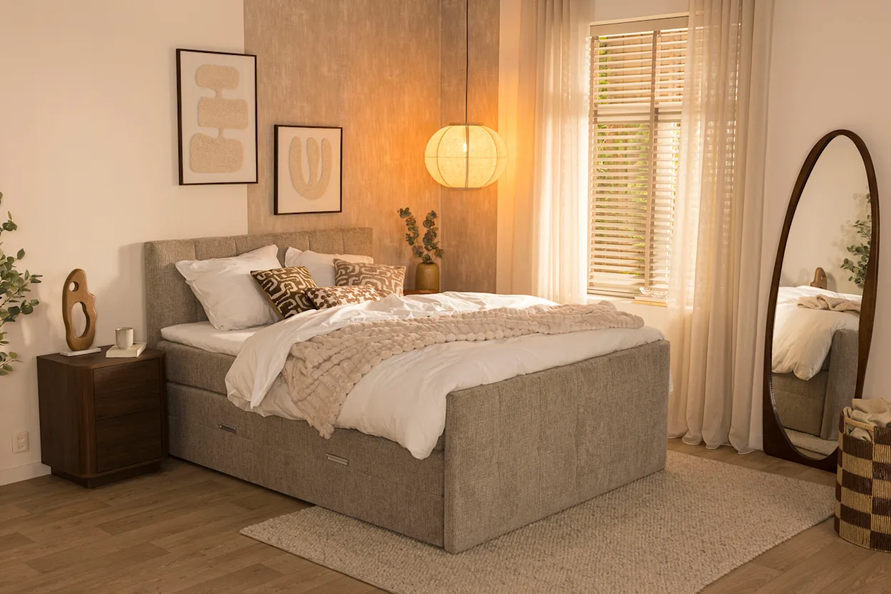 Taupekleurige boxspring Kanso met rustig hoofd- en voetbord in een lichte slaapkamer