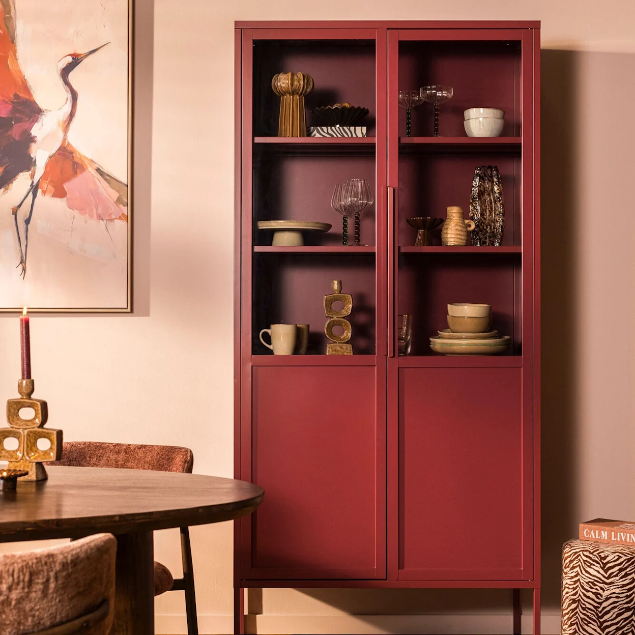 Bordeaux vitrinekast Renee in een eetkamer, gevuld met servies en woondecoratie.