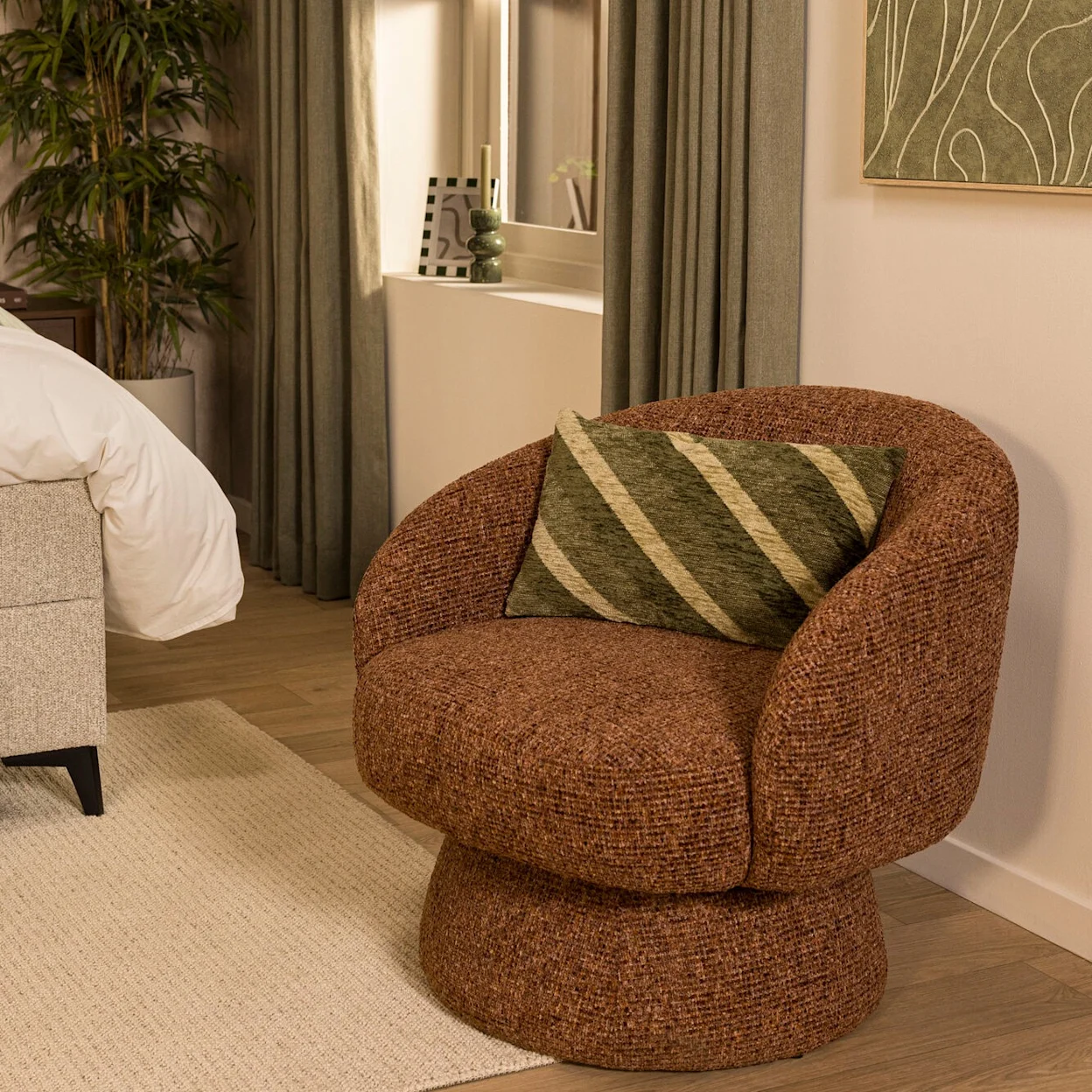 Terra kleurige ronde fauteuil en groen sierkussen in een sfeervolle slaapkamer.