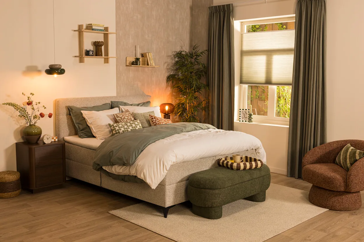 Moderne slaapkamer met een greige boxspring, sierkussens, houten wandplanken en warme sfeerverlichting.