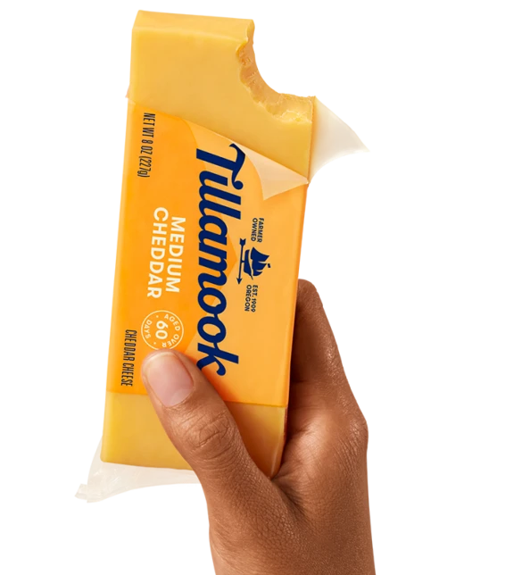 Tillamook Medium Cheddar Cheese block in hand