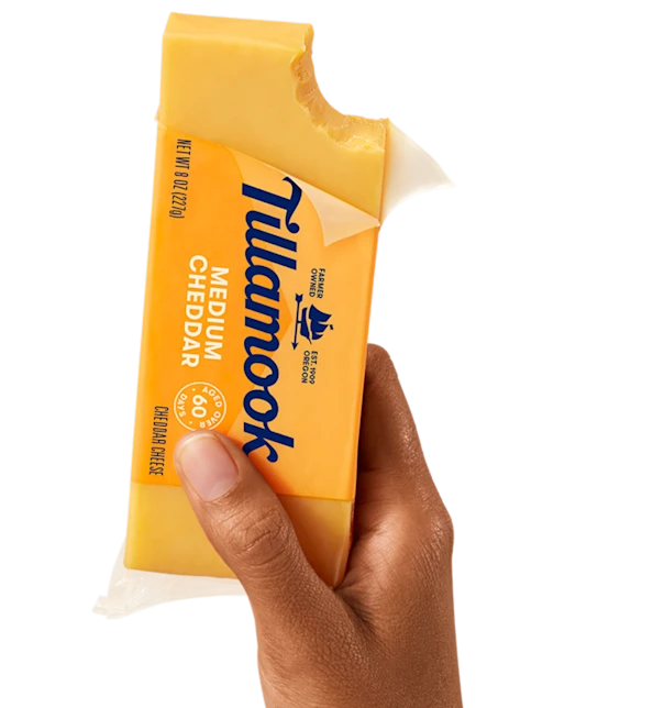 Tillamook Medium Cheddar Cheese block in hand
