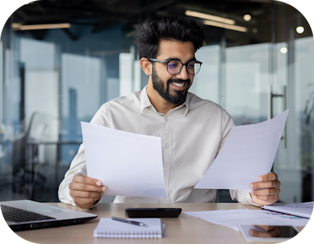 man with glasses holding paperwork while examining