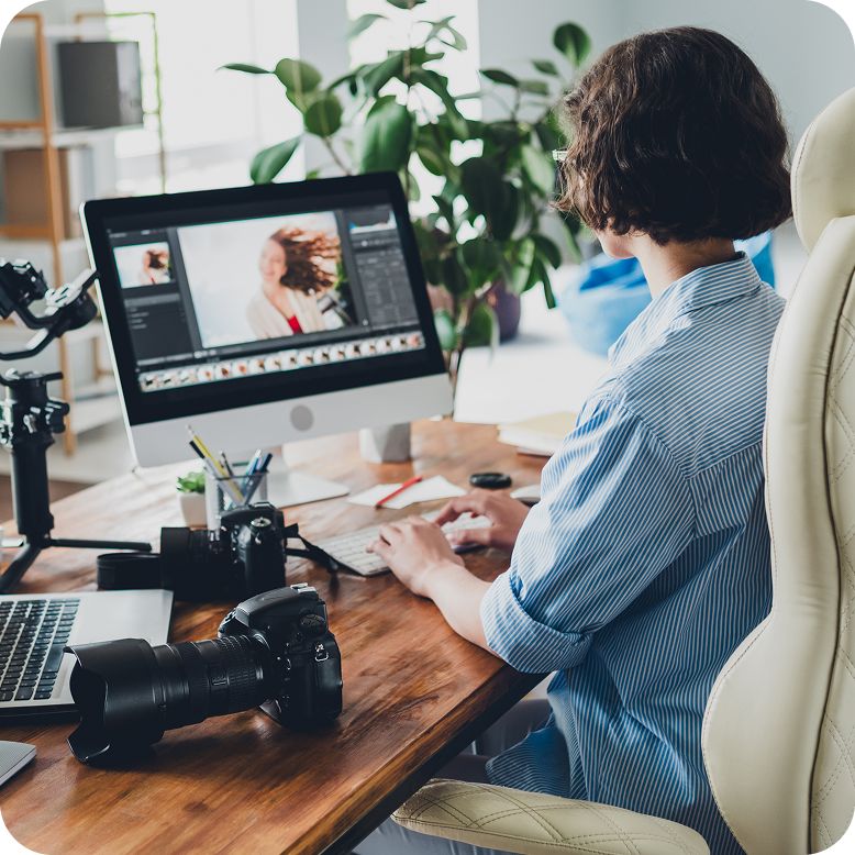 woman working on personal computer with a dslr camera next to her