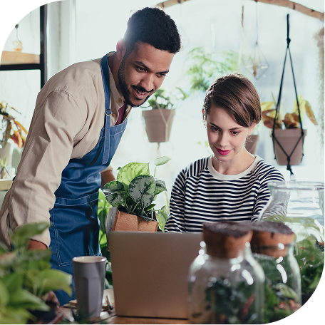 man with apron looking at a laptop of a woman in a gardening store setting