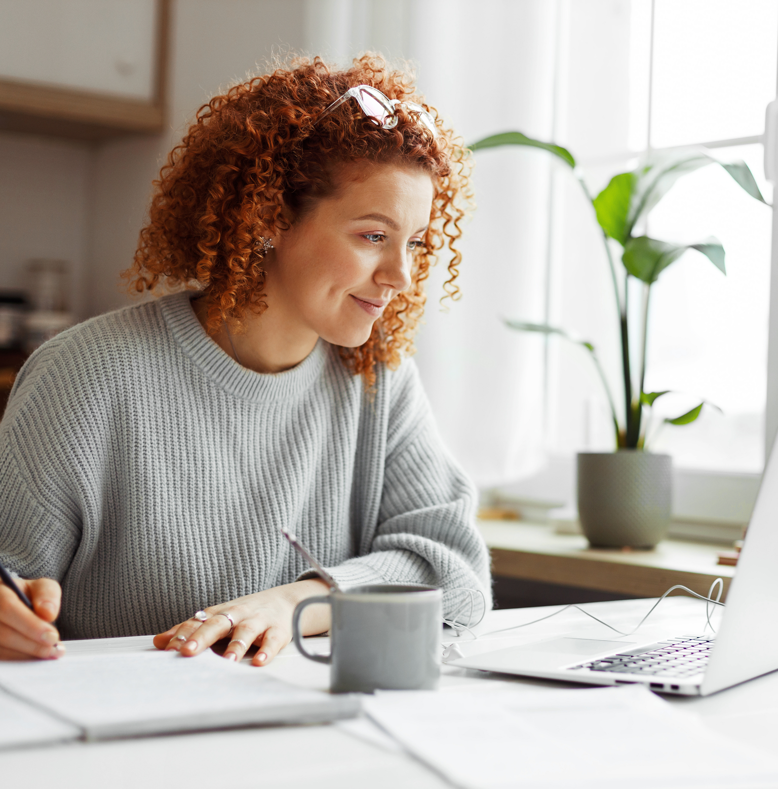 A girl smiling and looking at laptop while writing