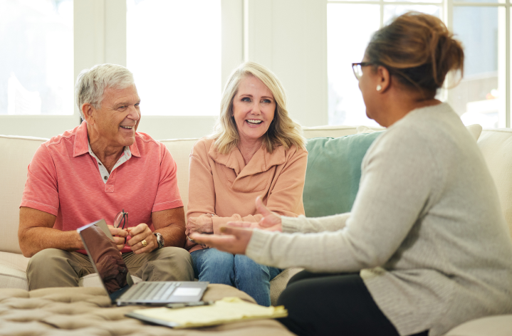 happy older couple sitting on couch talking to a friend