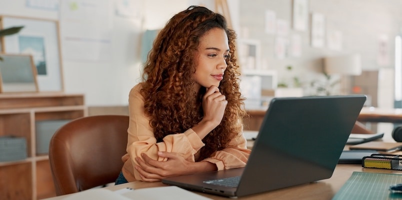 Woman in office staring at comparing reading 2025 tax law changes article to be prepared for tax season.