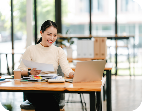 woman holding paperwork while working on a laptop