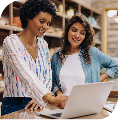 Two ladies talking while using laptop