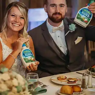 A couple at their wedding holding up bottles of Hidden Valley Ranch